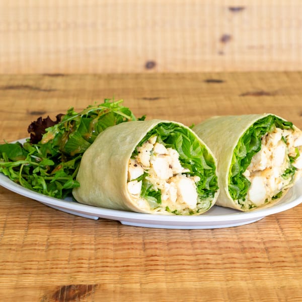 Two chicken Caesar wraps with fresh green lettuce and dressing, served with a side salad.