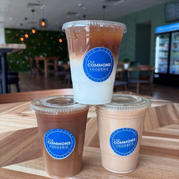 Three iced coffees from The Commons Fooderie, two on a table and one stacked on top.